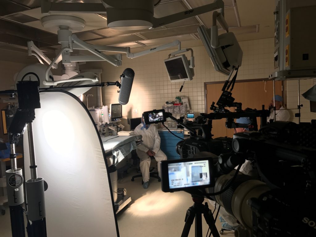FoxFury Nomad lights illuminate an interview in a dark surgical room. The lights are aimed at the wall and floor to provide softer background lighting